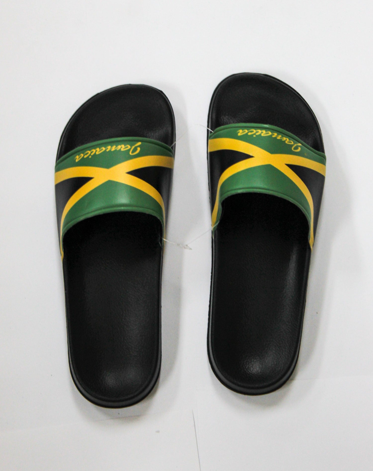 A pair of black slide sandals with the Jamaican flag colors on the straps, accompanied by the word Jamaica in yellow script.