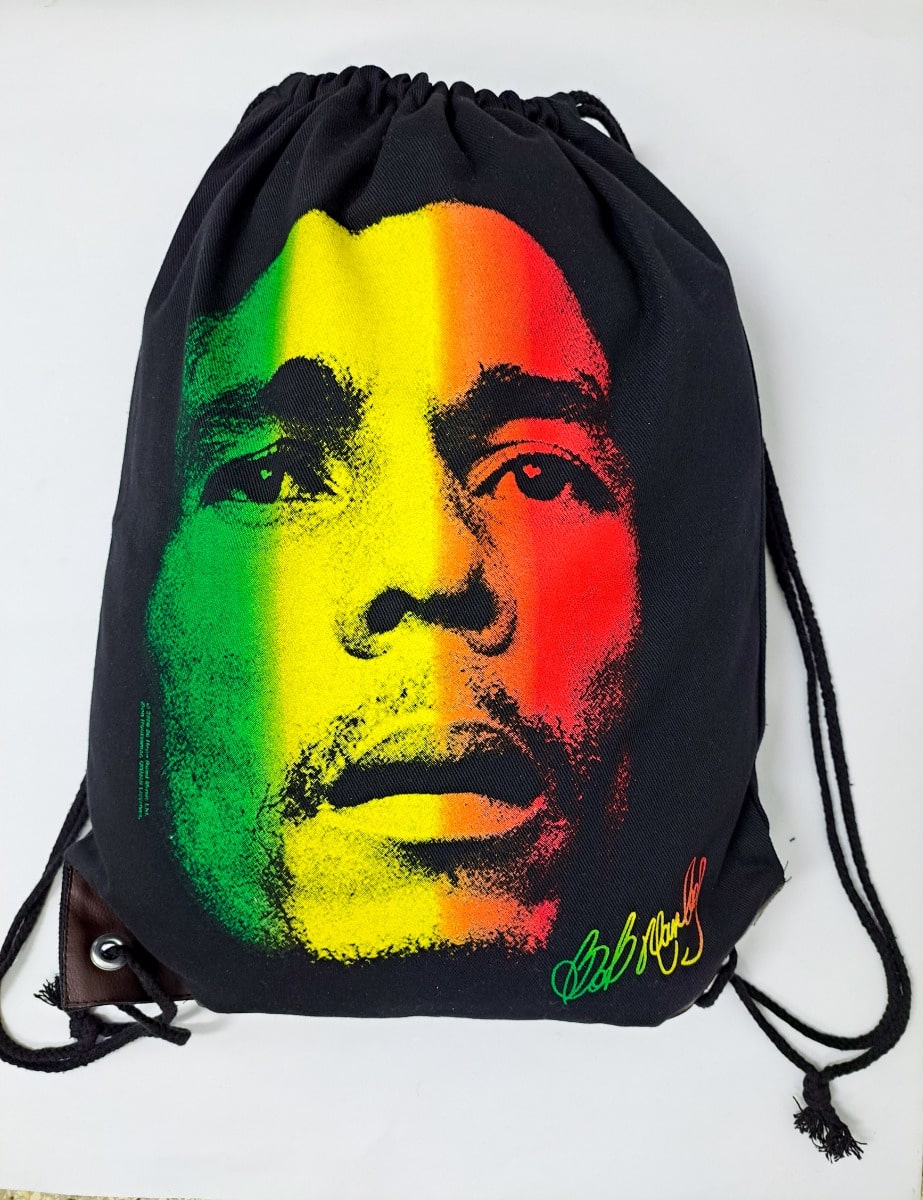 A black drawstring bag by 876 Worldwide showcases a stylized portrait in vibrant green, yellow, and red hues. The portrait predominantly covers the bag's surface, accented with an indistinct signature in the bottom corner.