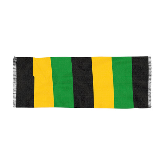A rectangular scarf featuring vertical block stripes in the Jamaican national colors of black, yellow, and green. The scarf has a soft fabric texture and a fine black and white fringed trim on both ends, set against a plain white background.