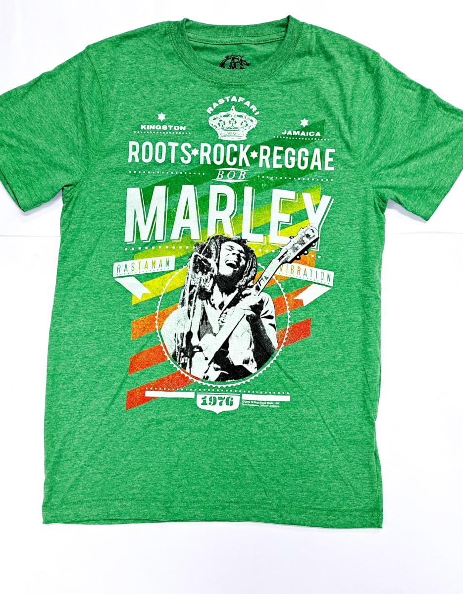 An 876 Worldwide reggae t-shirt in green boasts a lively graphic design with the words "Roots Rock Reggae" and "Marley," accompanied by a black and white image of a musician playing guitar. This shirt pays homage to music, including "Rastaman Vibration," 1976, while also highlighting Kingston, Jamaica.